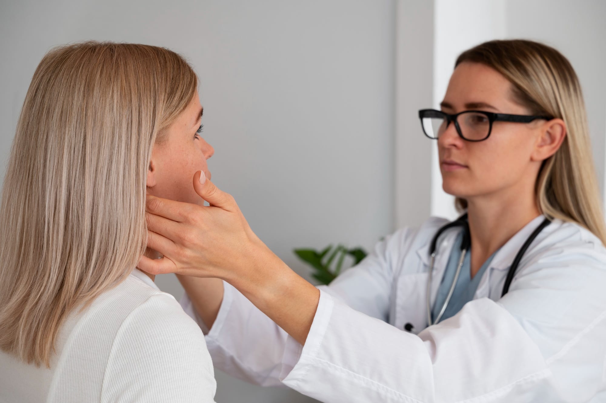 Doctor examining the neck of a female patient in a medical office