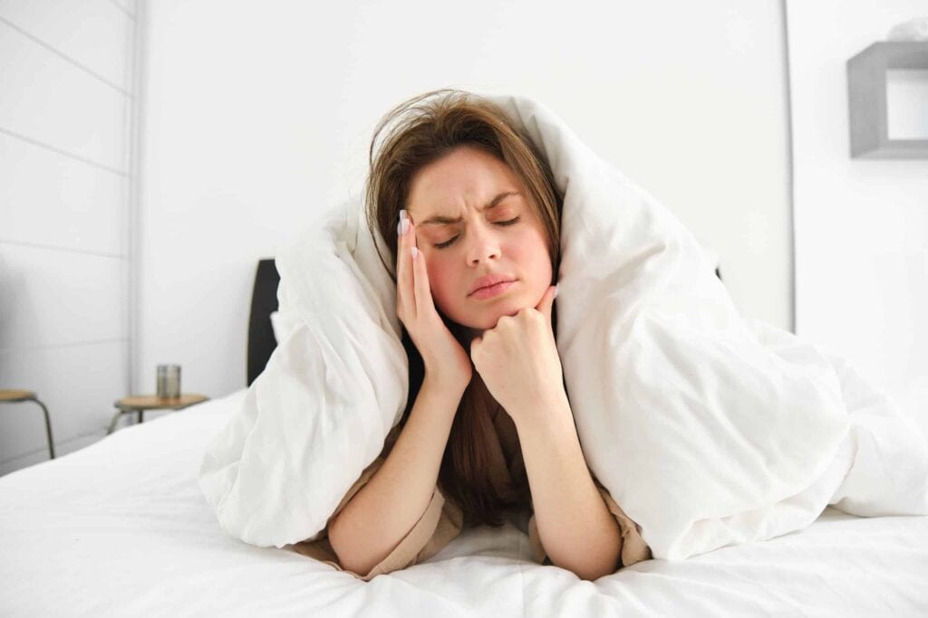 Woman waking up in bed with a jaw pain