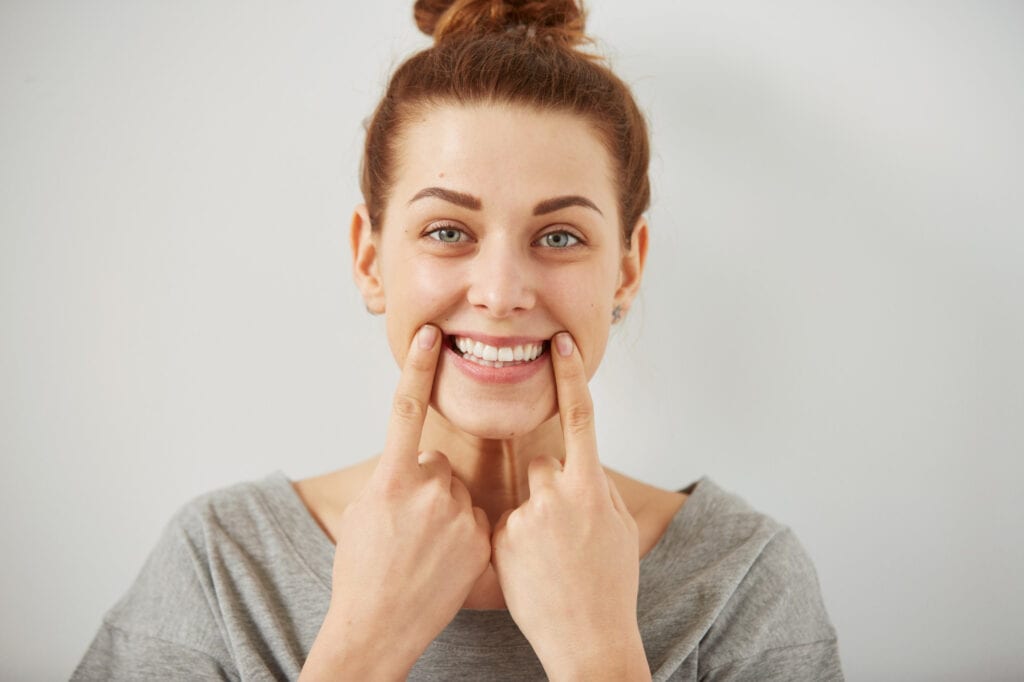 Woman smiling and pointing at her teeth with her fingers