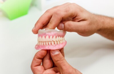 Person holding a set of artificial dentures