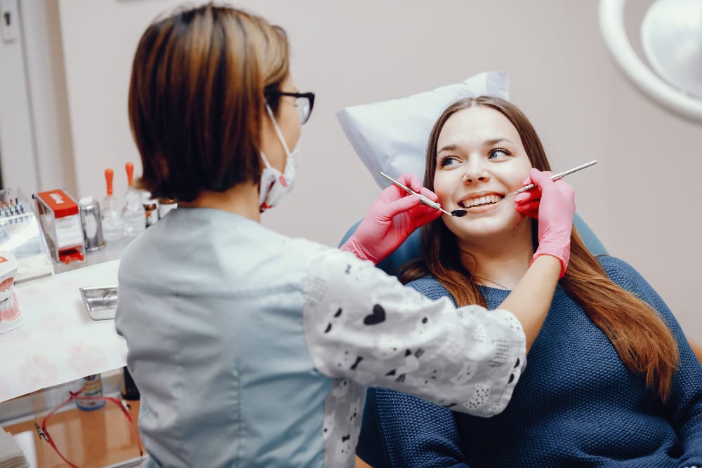 Dentist examining a smiling young woman’s teeth