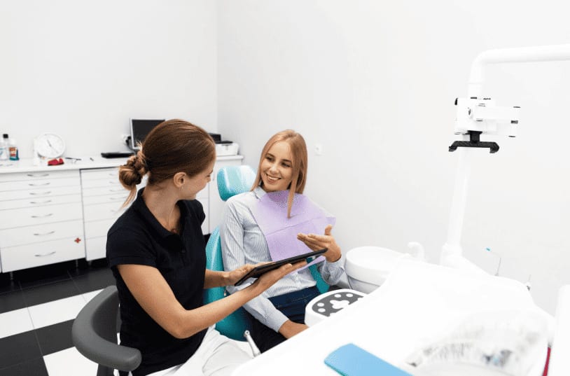 Dentist consulting with a young female patient in a dental chair
