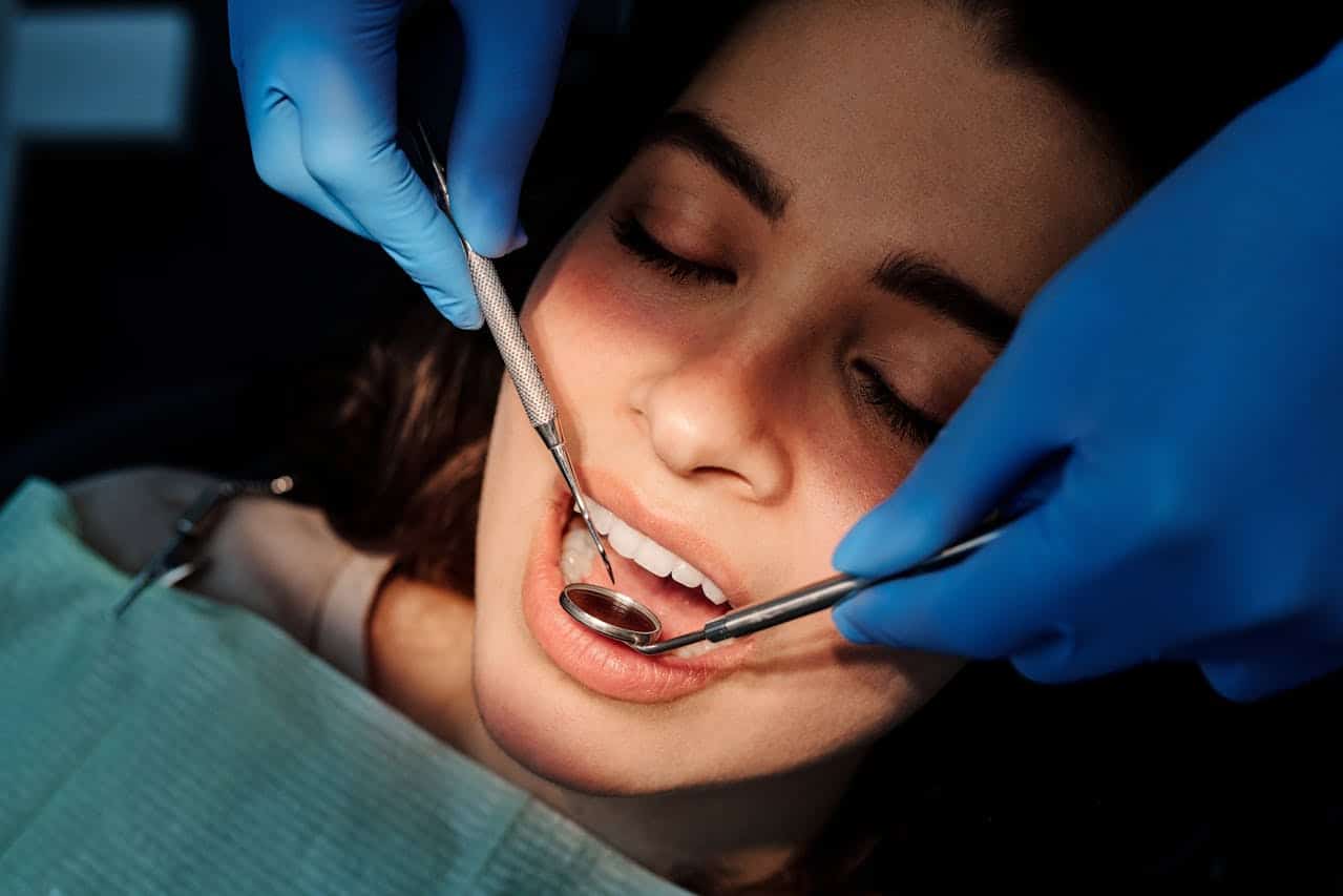 Close-up of a dentist performing a checkup and treatment on a patient, using dental instruments and wearing gloves