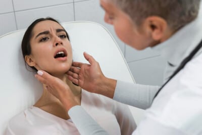 Doctor examining a patient's throat while she is lying on a medical bed