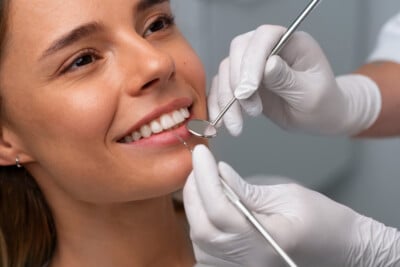 Woman smiling while a dentist examines her teeth
