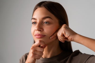 Young woman practicing facial yoga by massaging her chin