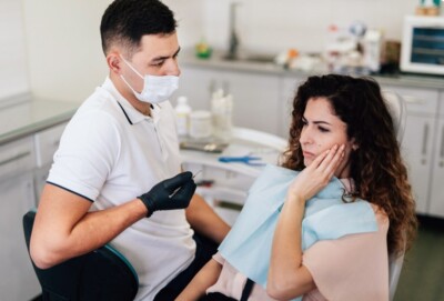 Dentist wearing a mask consulting with a woman in a dental chair