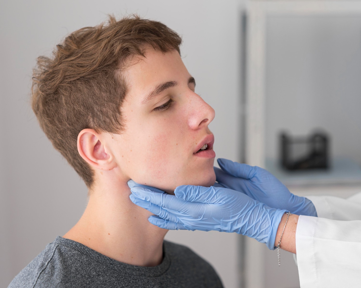 A young male patient receiving a neck examination by a healthcare professional