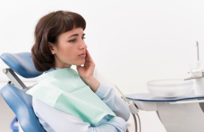 Woman sitting in a dental chair holding her jaw