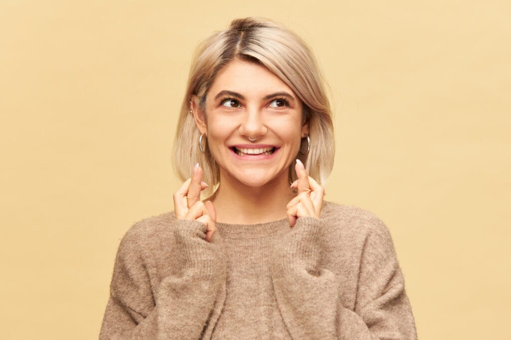 Woman smiling while touching both sides of her jaw with her fingers