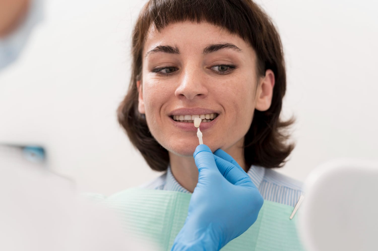 Dentist using a tooth shade guide to match the color of a patient’s teeth