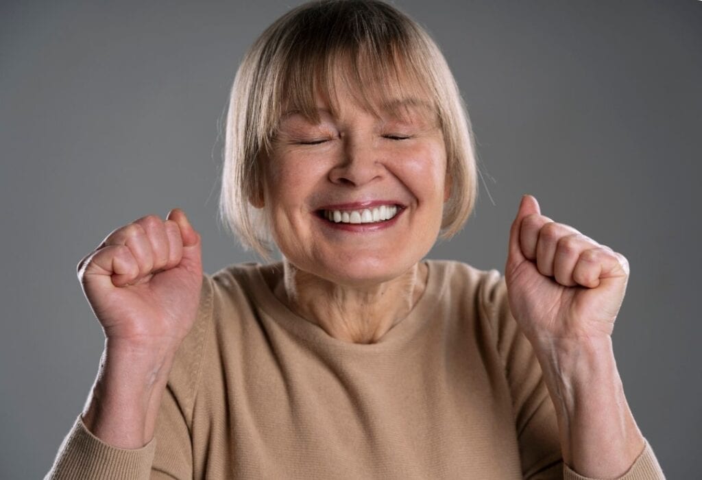 Smiling senior woman raising her fists in a joyful gesture
